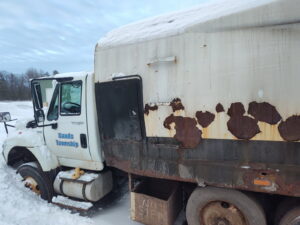Rusty truck in snowy Sands Township scene.