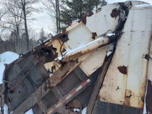 Close-up of rusty, damaged truck bed in snow.
